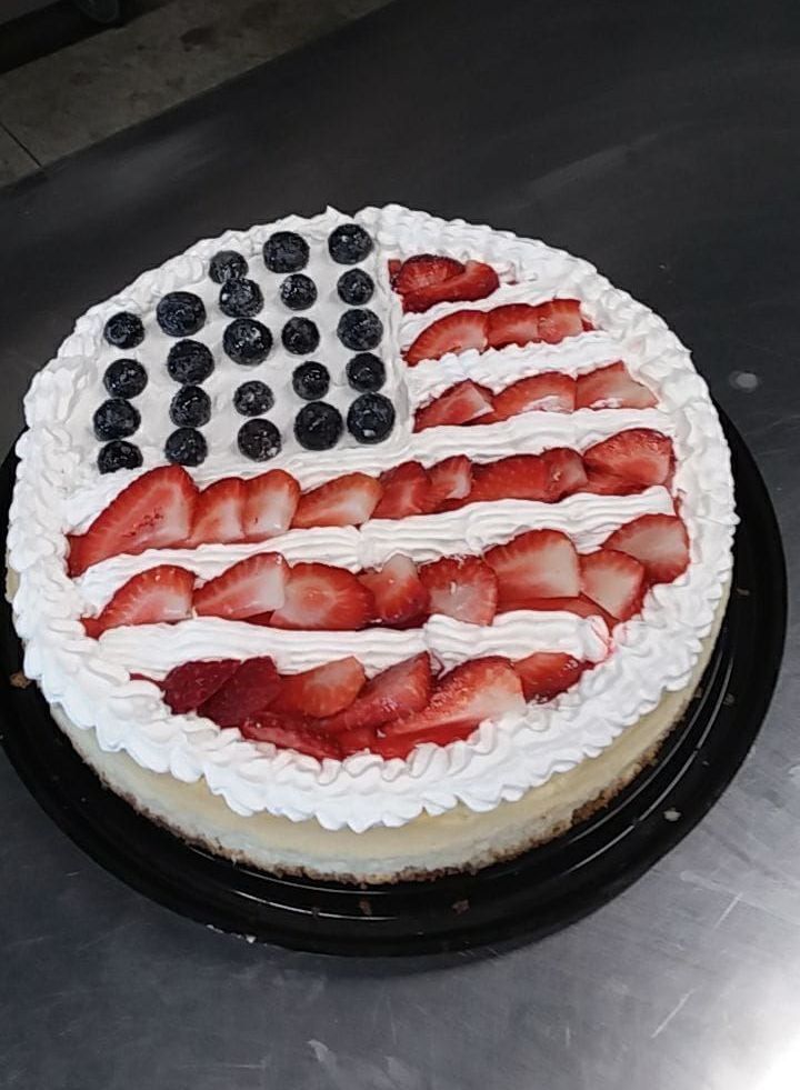 A cheesecake with strawberries and blueberries in the shape of an american flag.