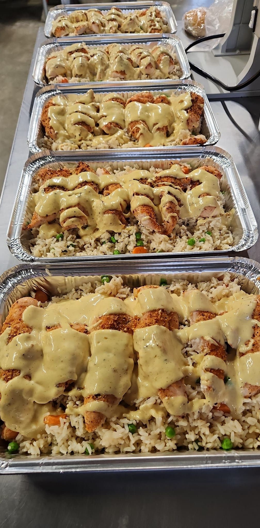 A row of aluminum foil containers filled with food on a table.