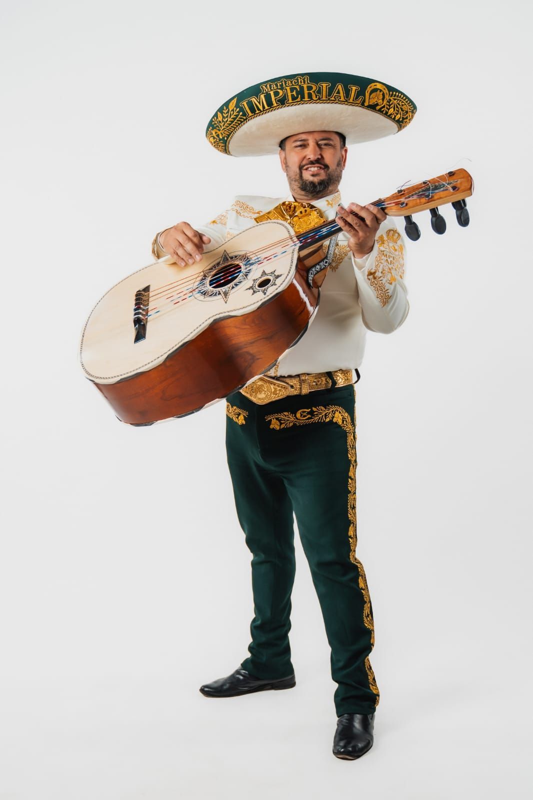 Un músico de mariachi, ataviado con un traje tradicional blanco y verde con bordados dorados