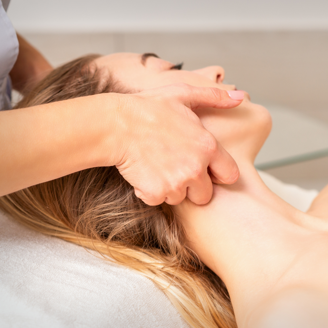 Person receiving a neck massage on a white surface, with hands massaging the neck.