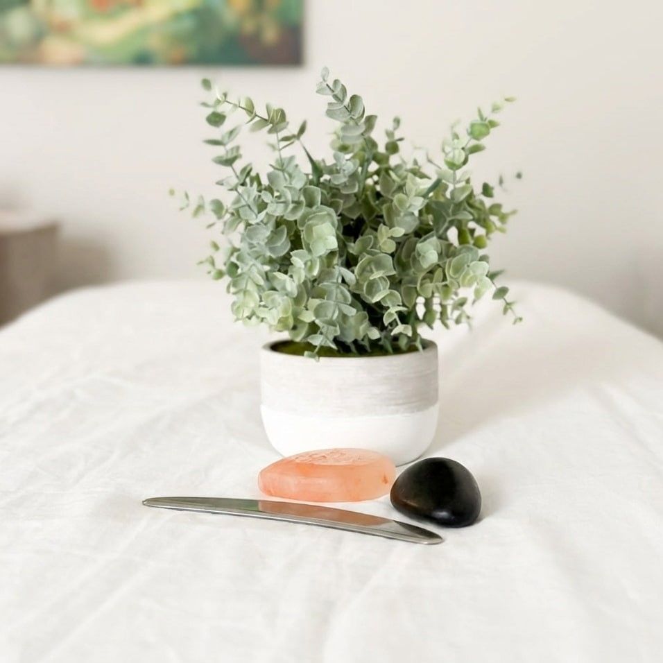 Blue foam roller and small ball on a pink mat with a wooden surface in the corner.