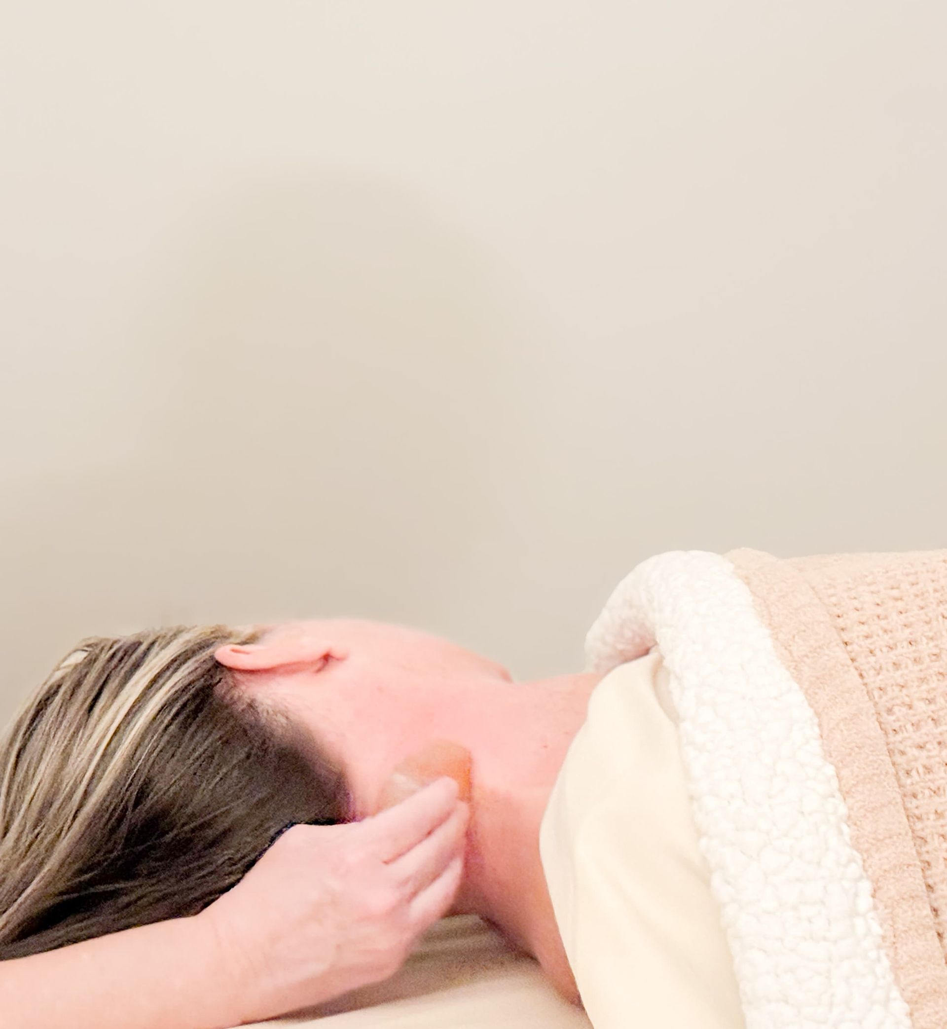 Person receiving a hot stone massage, face down on a massage table.