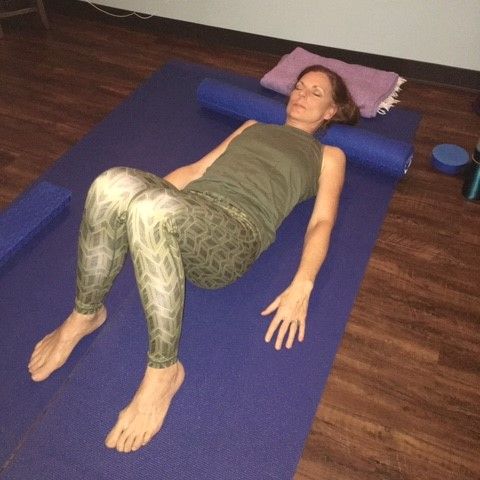 Woman in yoga pose, hands in prayer, legs crossed, on mat.