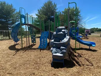 A playground with a slide and a rock climbing wall
