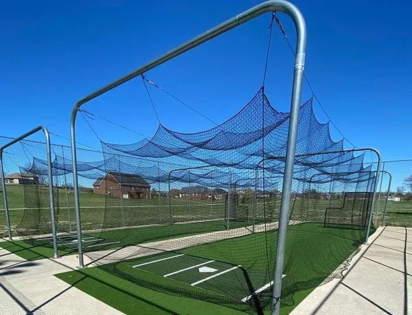 A baseball net is sitting on top of a baseball field.