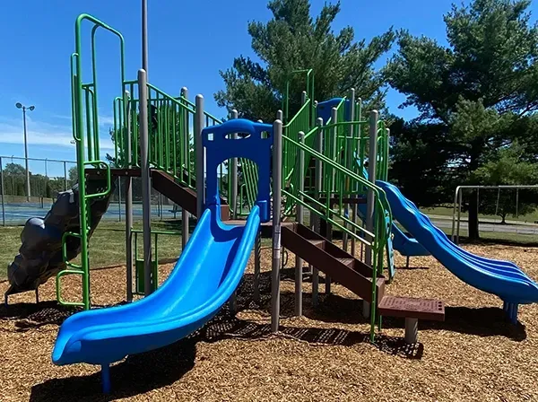 A playground with blue and green slides and stairs