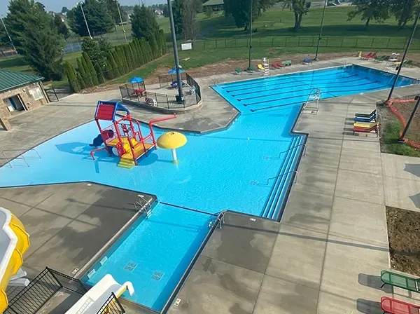 Aerial view of a public swimming pool with water slides and lane markers.