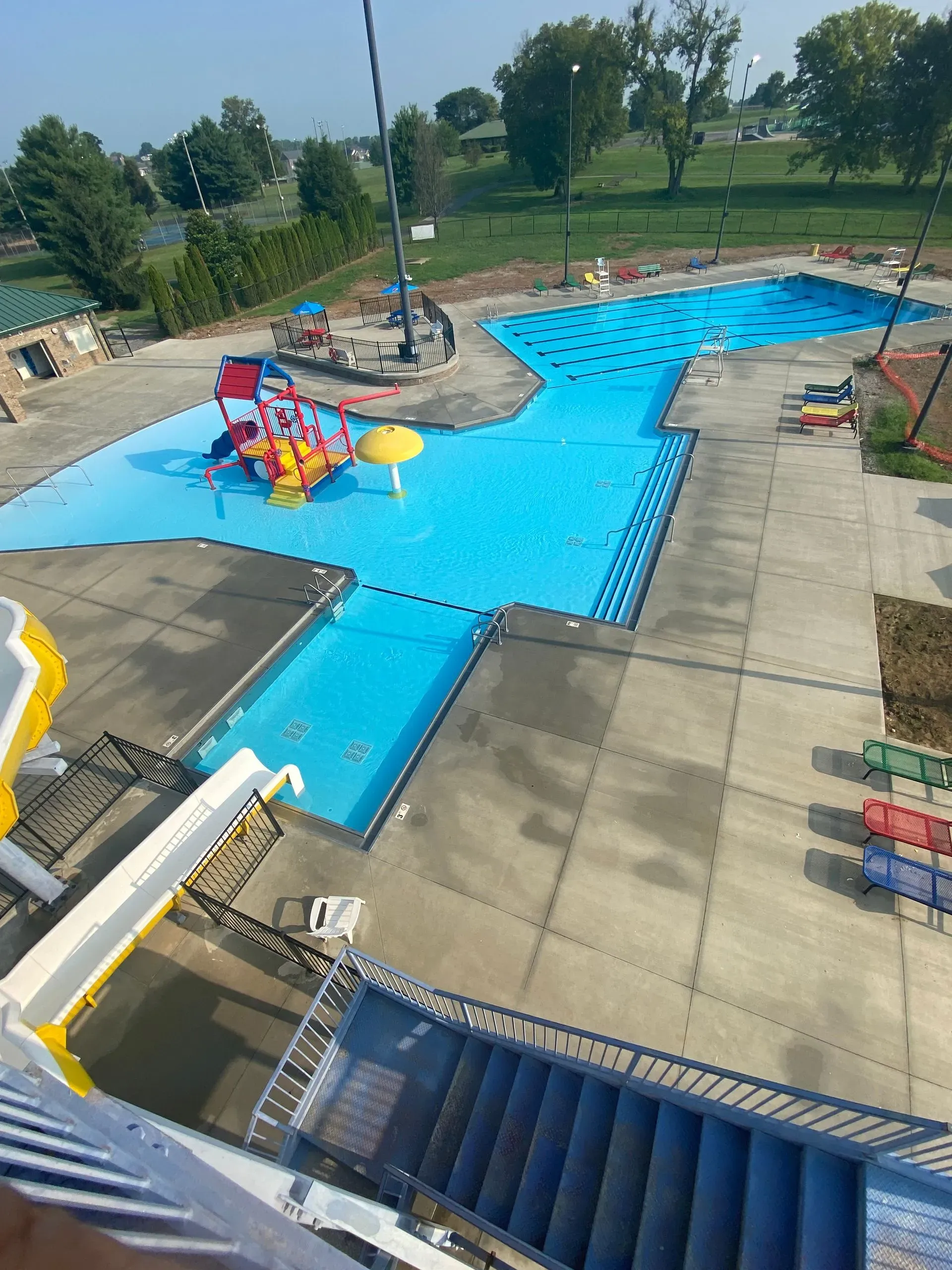 Aerial view of a water park with a blue pool, slides, and a colorful play structure.