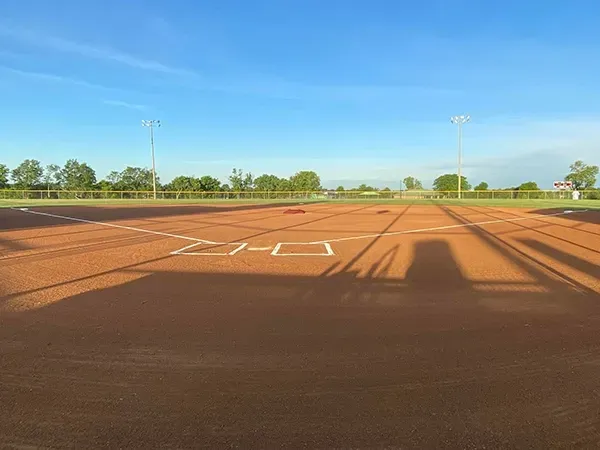 An empty baseball field with a blue sky in the background.