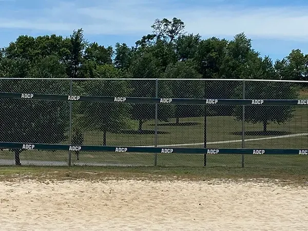 A volleyball net in a park with trees in the background