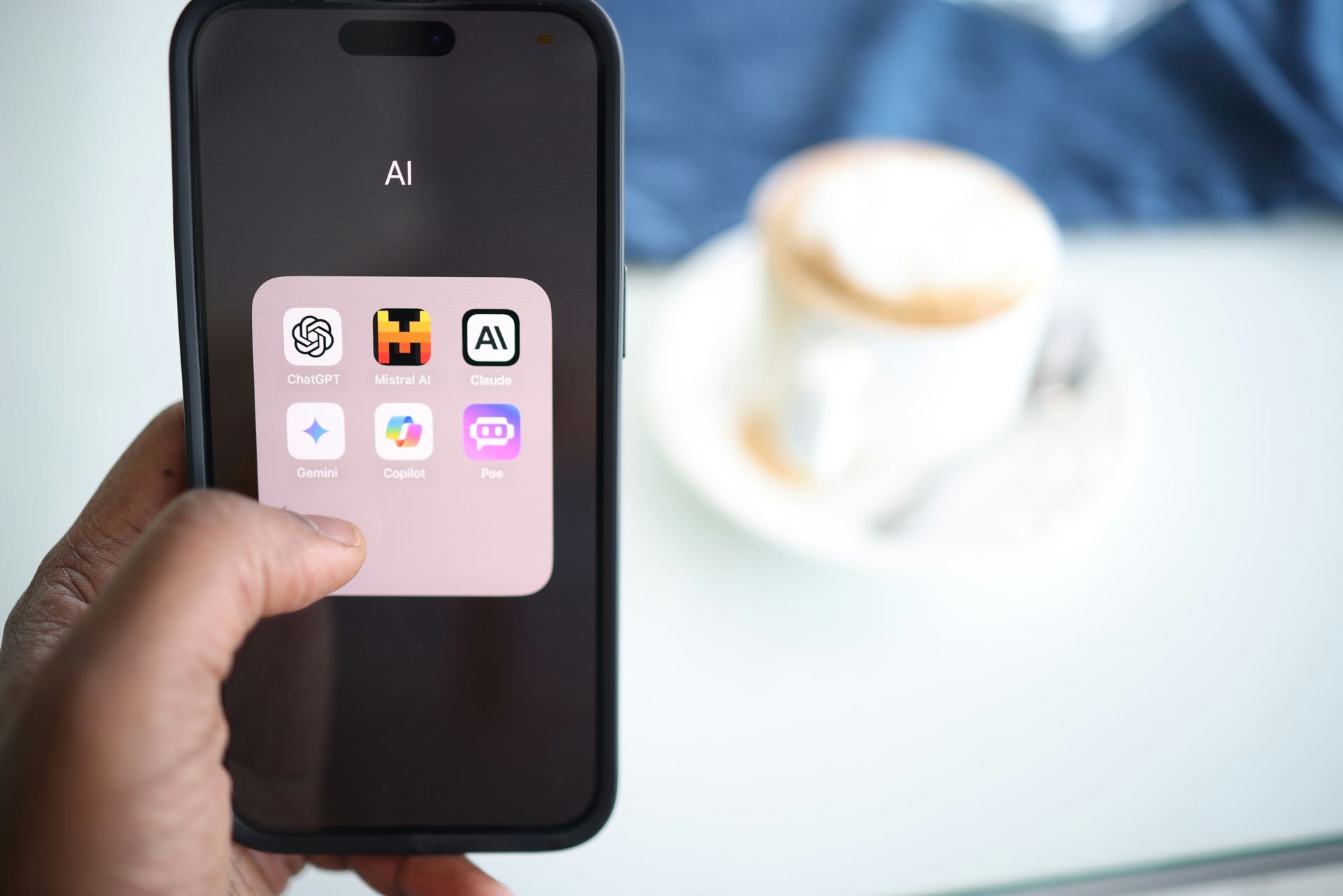 A person is holding a cell phone in front of a cup of coffee.