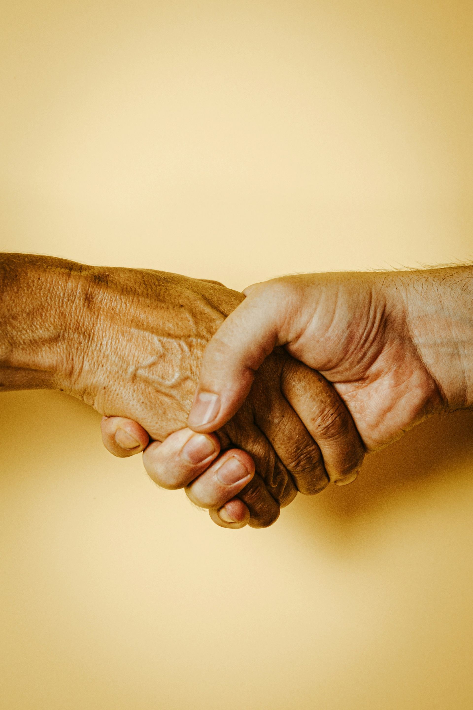 Two men are shaking hands on a yellow background.