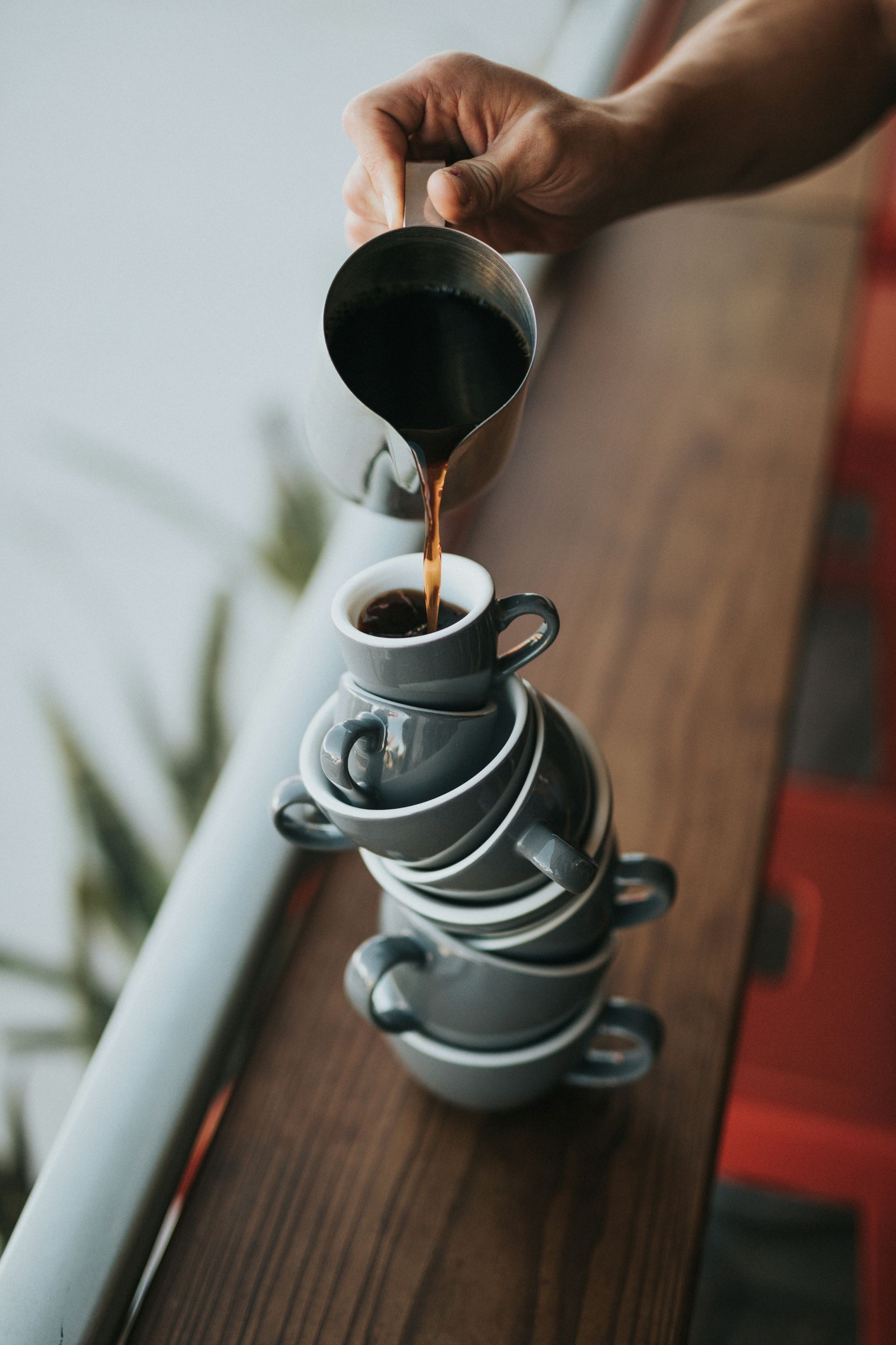 A person is pouring coffee into a stack of cups.
