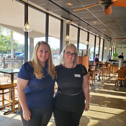 Two women are standing next to each other in a restaurant.