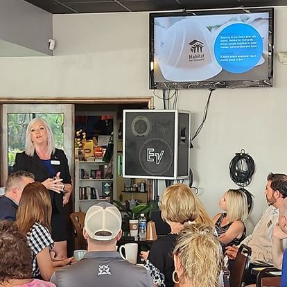A woman is giving a presentation to a group of people in a restaurant.