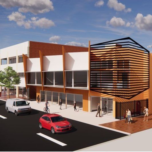 A red car is parked in front of a large building