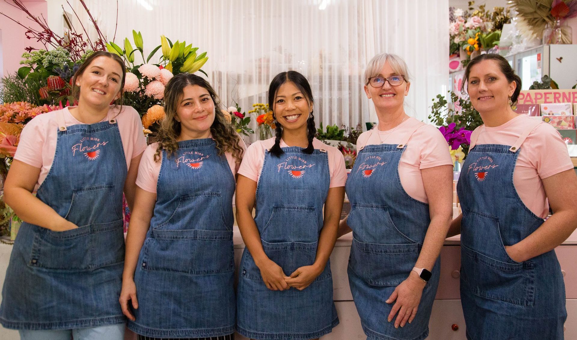 Joyful team photo at Darwin's flower shop, surrounded by vibrant blooms, embodying happiness and camaraderie.1