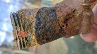 A person is holding a piece of rusty metal in their hand.