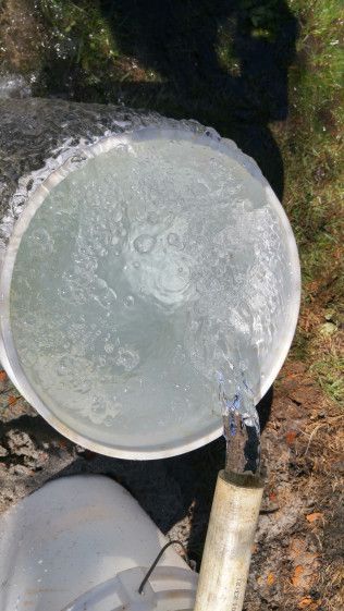 A bucket of water is being poured into a pipe.