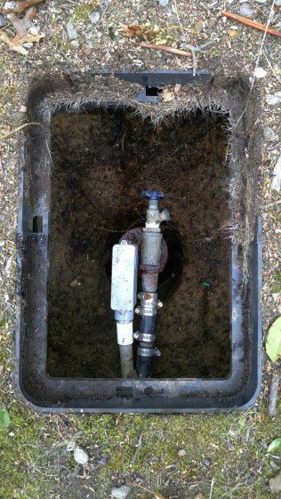 A close up of a faucet in a box on the ground.