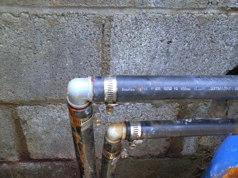 A close up of a water pipe connected to a brick wall.