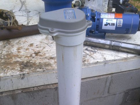 A blue pump is sitting next to a white pipe