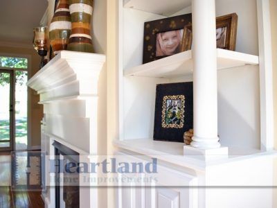 A living room with a fireplace and shelves that say heartland