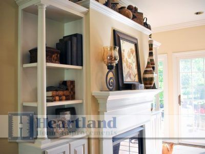 A living room with a fireplace and a heartland logo on the wall