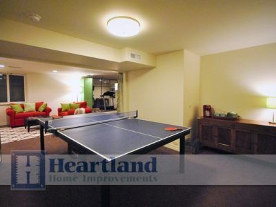 A basement with a ping pong table and a sign that says heartland home improvements