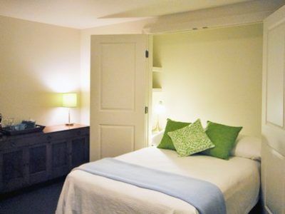 A bedroom with a white bed and green pillows