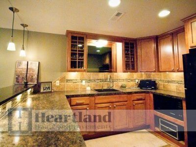 A kitchen with wooden cabinets and granite counter tops with the word heartland on the bottom