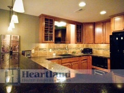 A kitchen with wooden cabinets and a black refrigerator