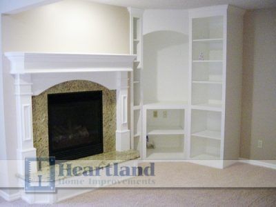 A living room with a fireplace and a heartland home improvements logo