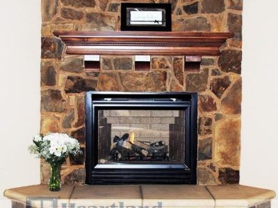 A fireplace with a vase of flowers in front of it
