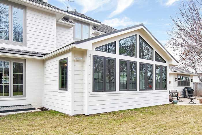 A white house with a sunroom and a lot of windows.