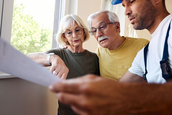 An older couple is looking at a piece of paper with a man.