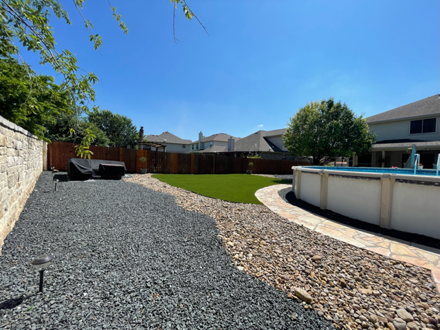 A backyard with a swimming pool and a gravel path