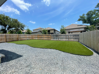 A backyard with a grassy area and a wooden fence