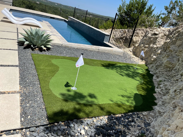 A putting green in front of a swimming pool