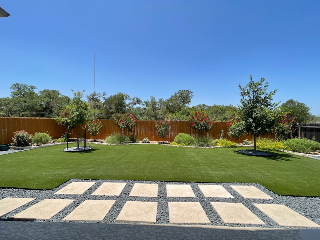 A lush green lawn with a wooden fence in the background