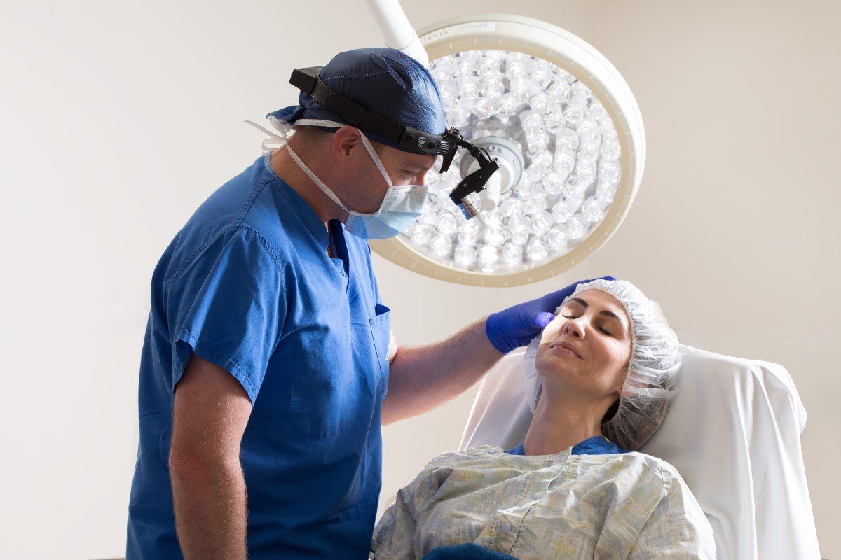 A surgeon is touching the forehead of a patient in an operating room.