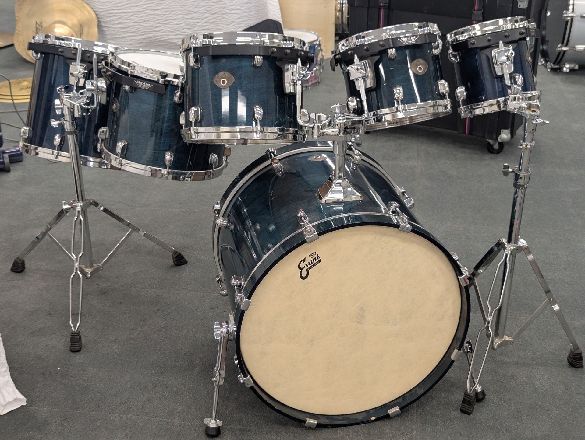 Blue drum set on stands, set up in a room.