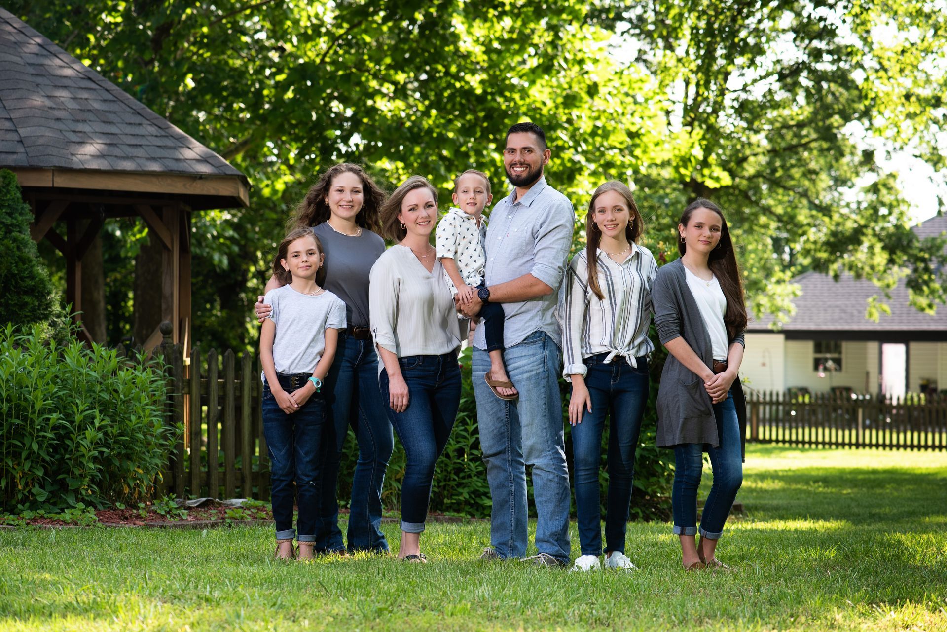 Man wearing glasses and a blue shirt smiles outdoors.
