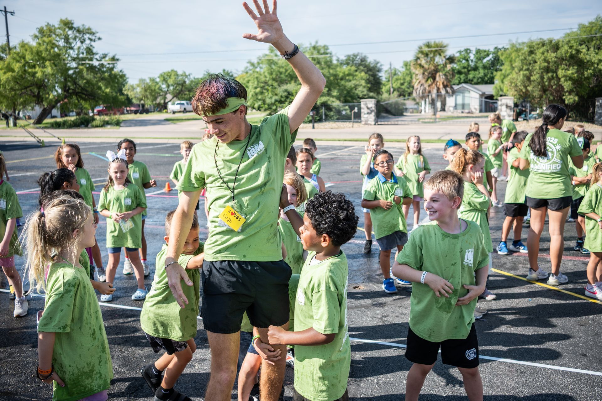 Children cheering, some with open mouths and raised fists, in a room with purple seating.