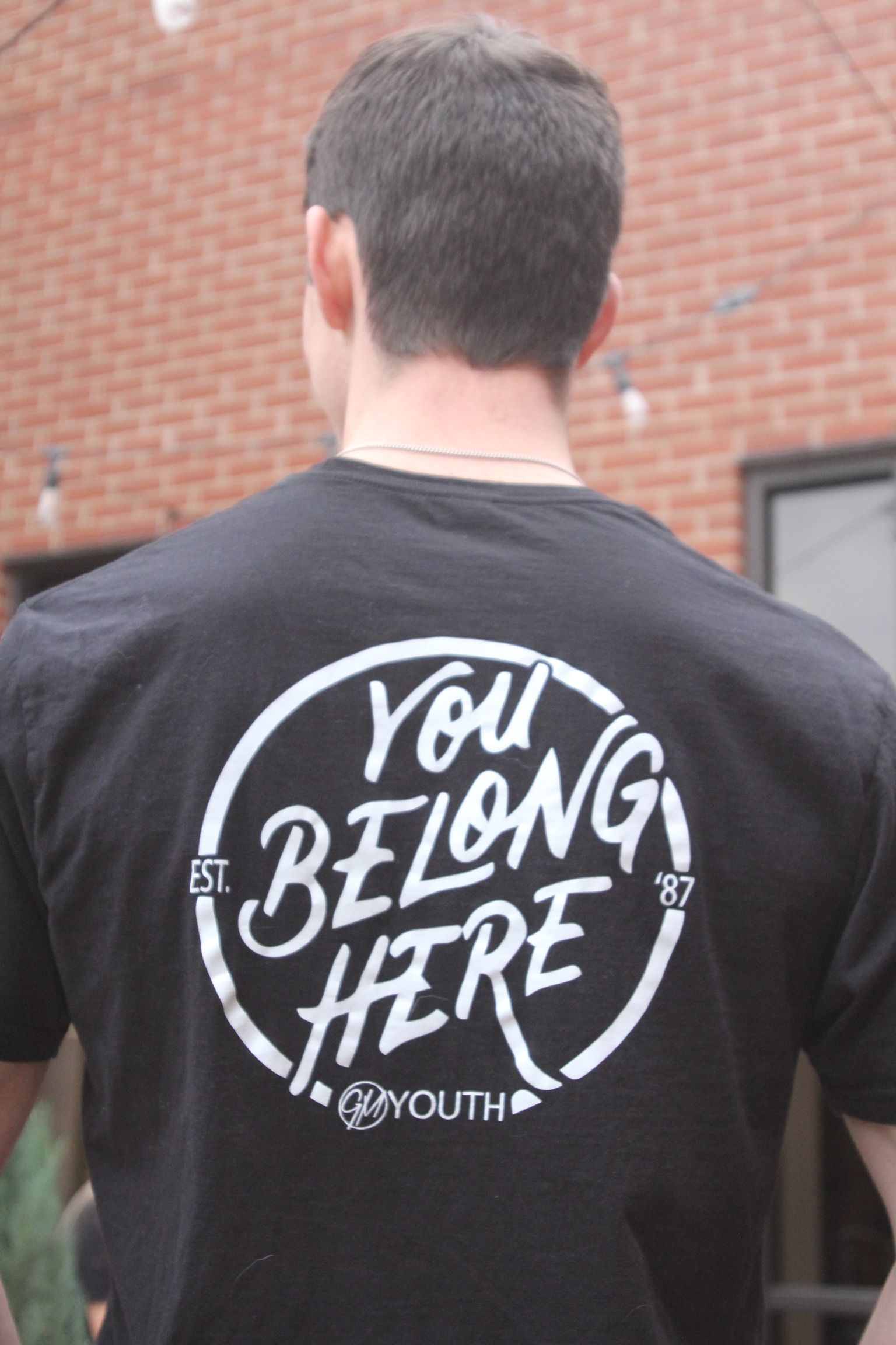 Man wearing a black t-shirt with a white circle design that says 