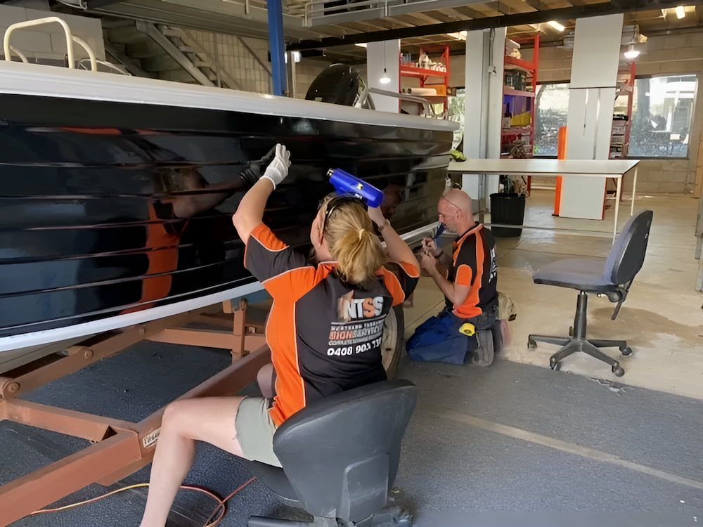 A Man And A Woman Are Working On A Boat In A Factory — Northern Territory Sign Services in Winnellie, NT