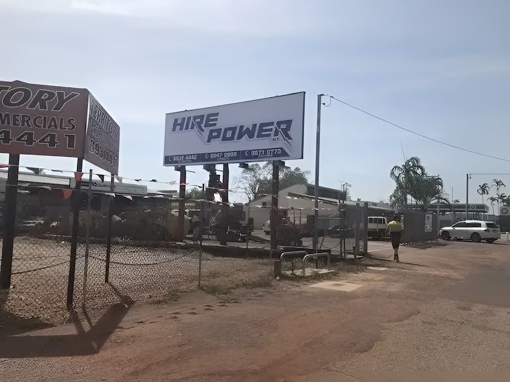 A Billboard For Hire Power Is On The Side Of A Dirt Road — Northern Territory Sign Services in Winnellie, NT