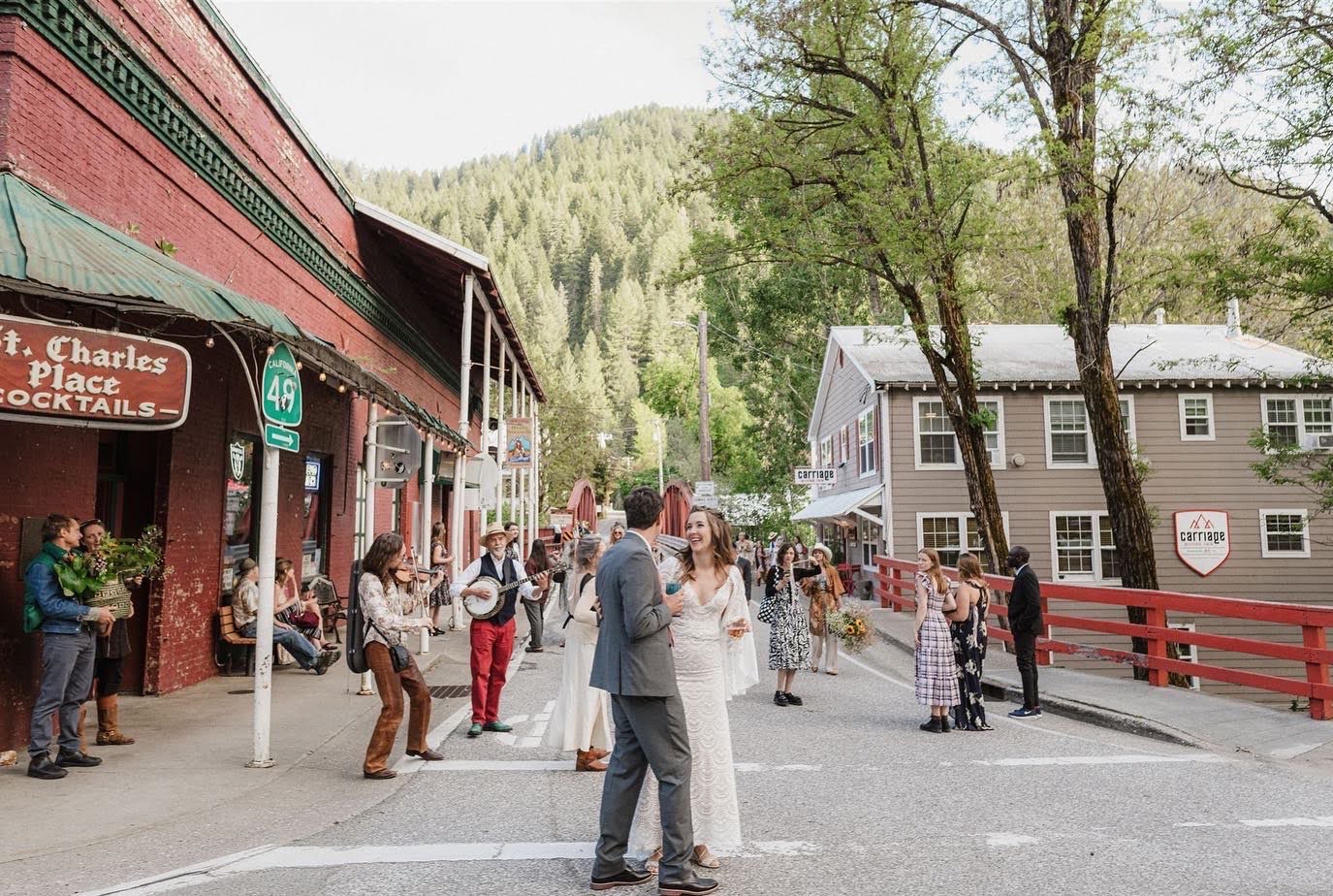 A bride and groom are dancing on a street in a small town.