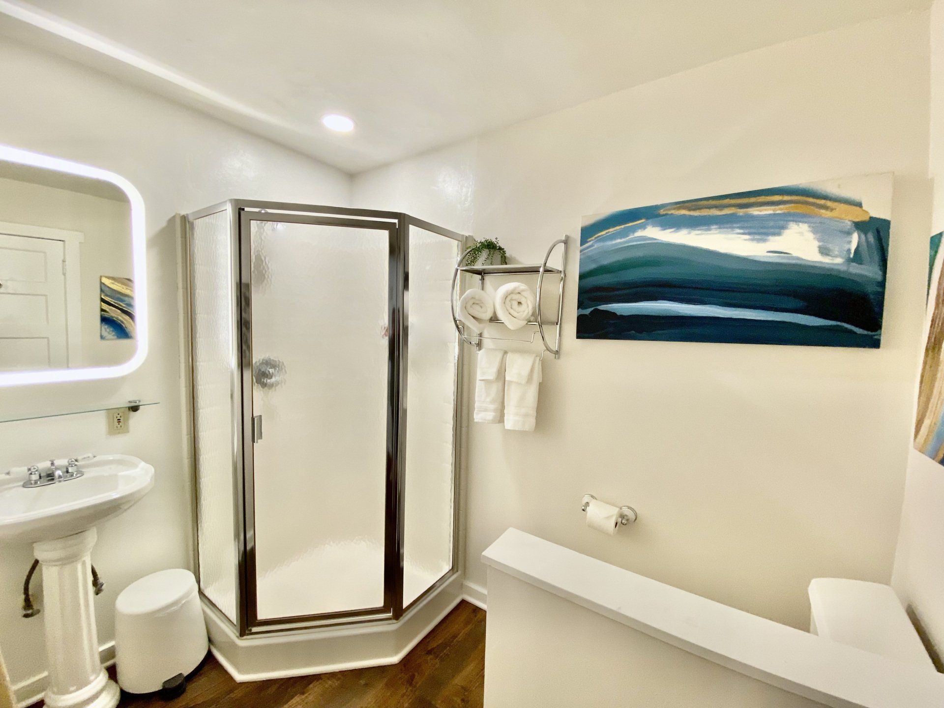 A bathroom with a shower , sink , mirror and stairs.