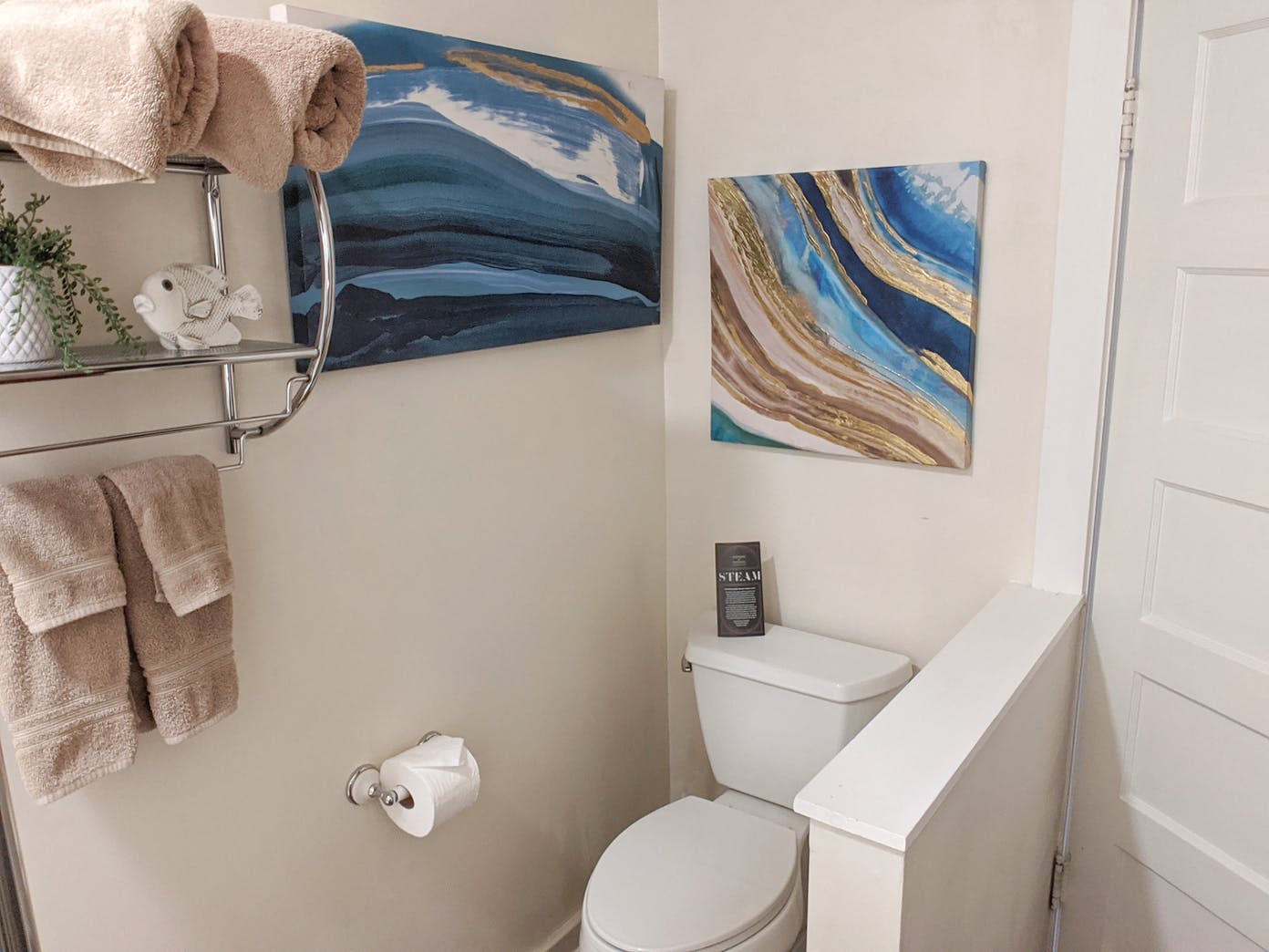 A bathroom with a toilet and a painting on the wall.